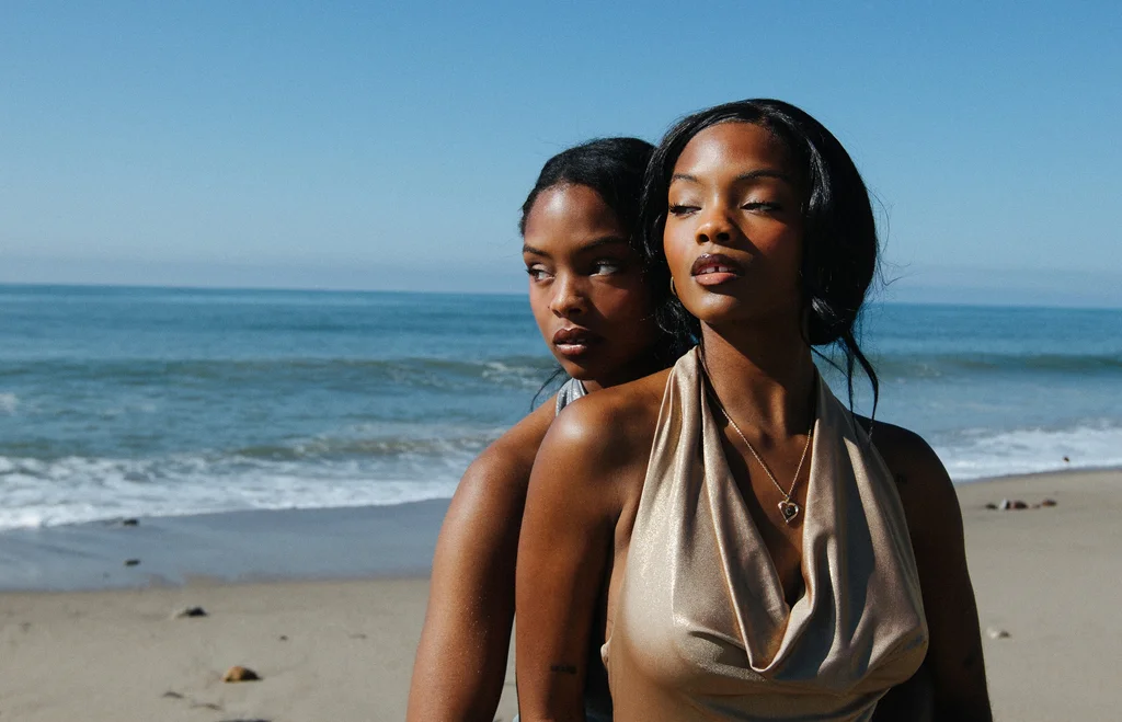 Two figures in metallic styling beside the ocean
