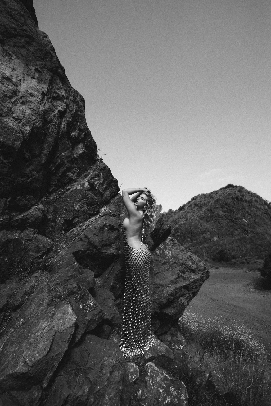 Black-and-white fashion portrait framed by rugged rocks