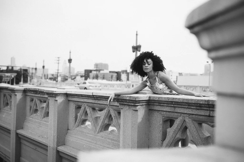 Black-and-white fashion portrait against a stone bridge balustrade