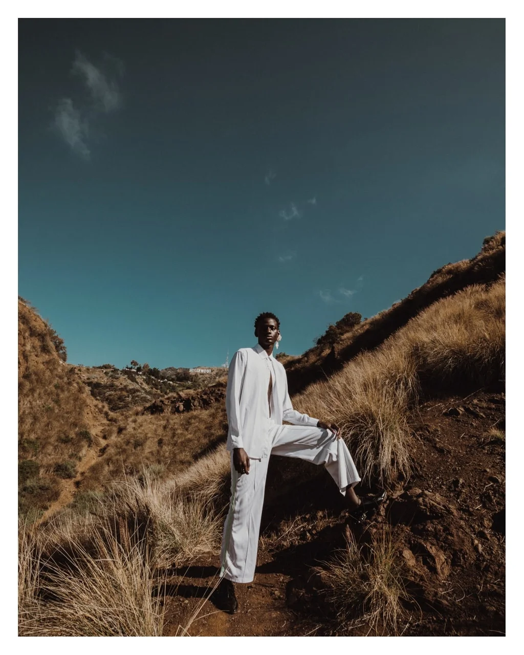 Figure in white on a dry hillside beneath a turquoise sky