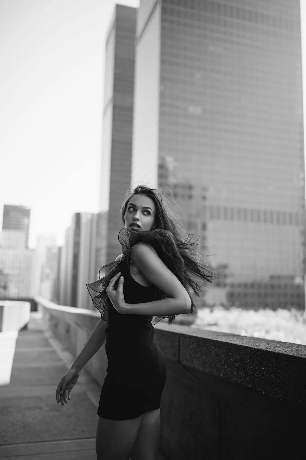 Black-and-white rooftop portrait against city towers