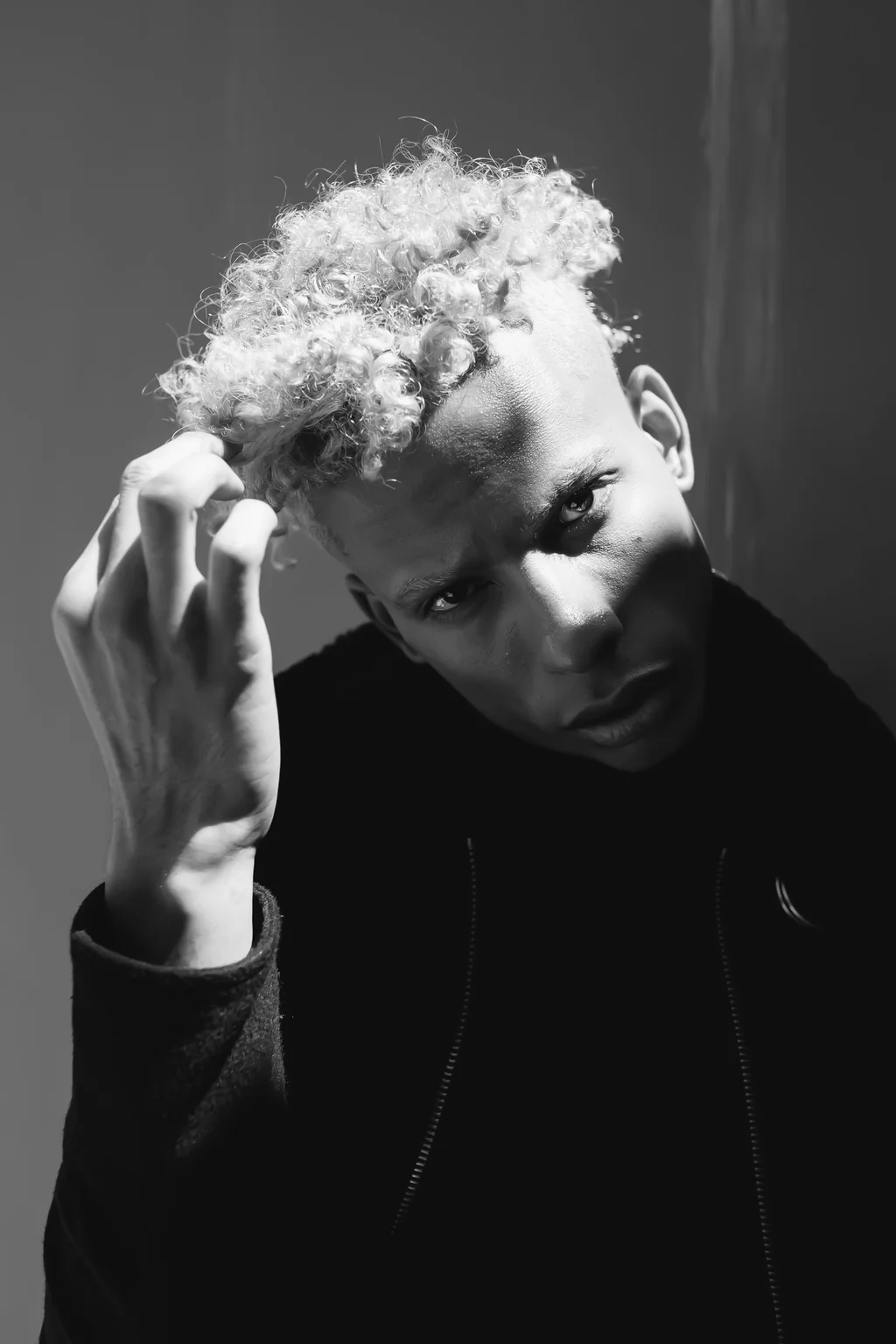 A close black-and-white portrait with cropped curls