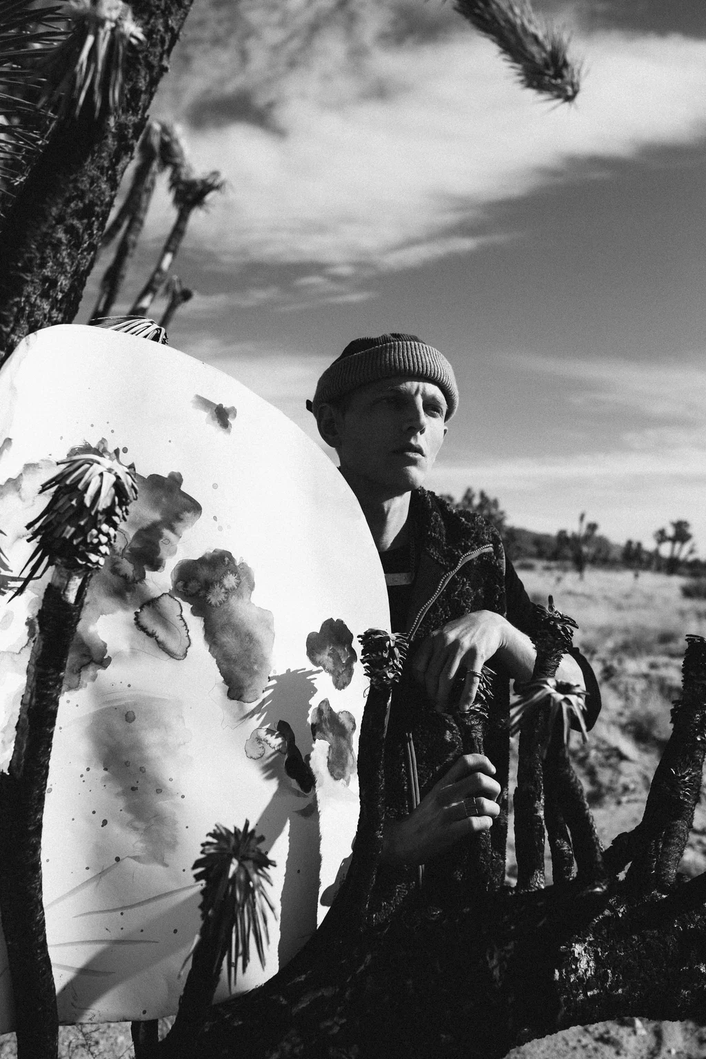 Black-and-white portrait with a patterned board among desert trees