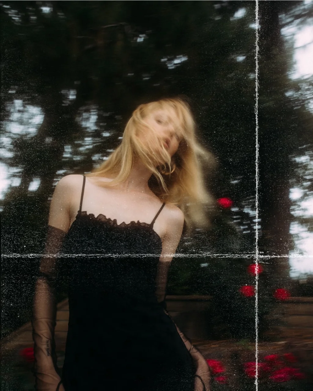 Motion-blurred portrait in a black dress among trees and flowers