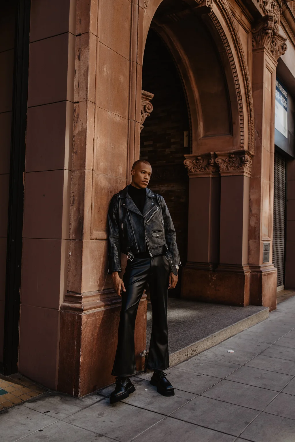 Dark tailoring beneath an ornate stone archway