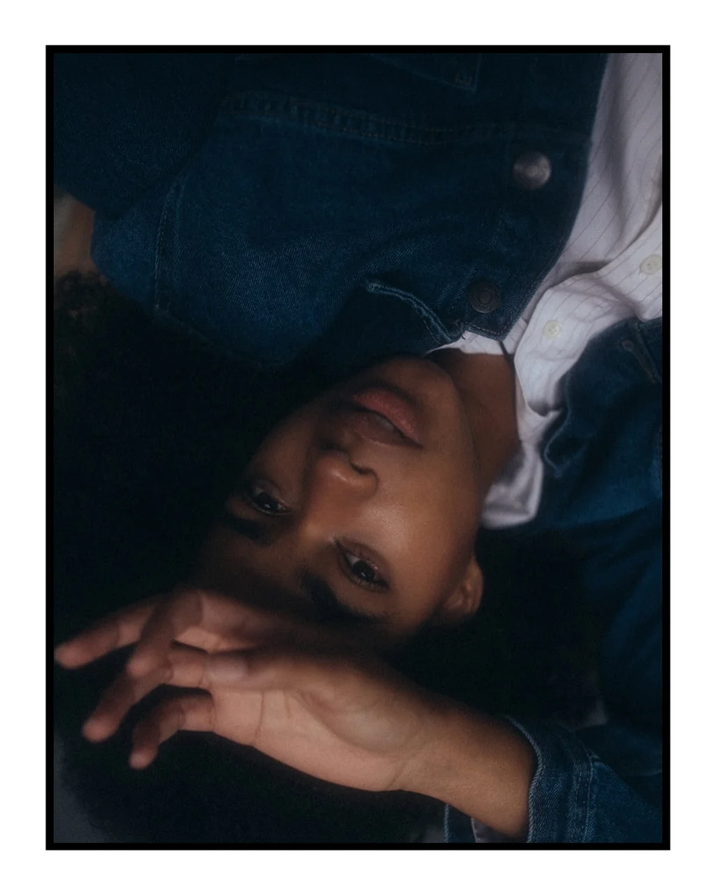 Inverted portrait in denim framed by raised hands