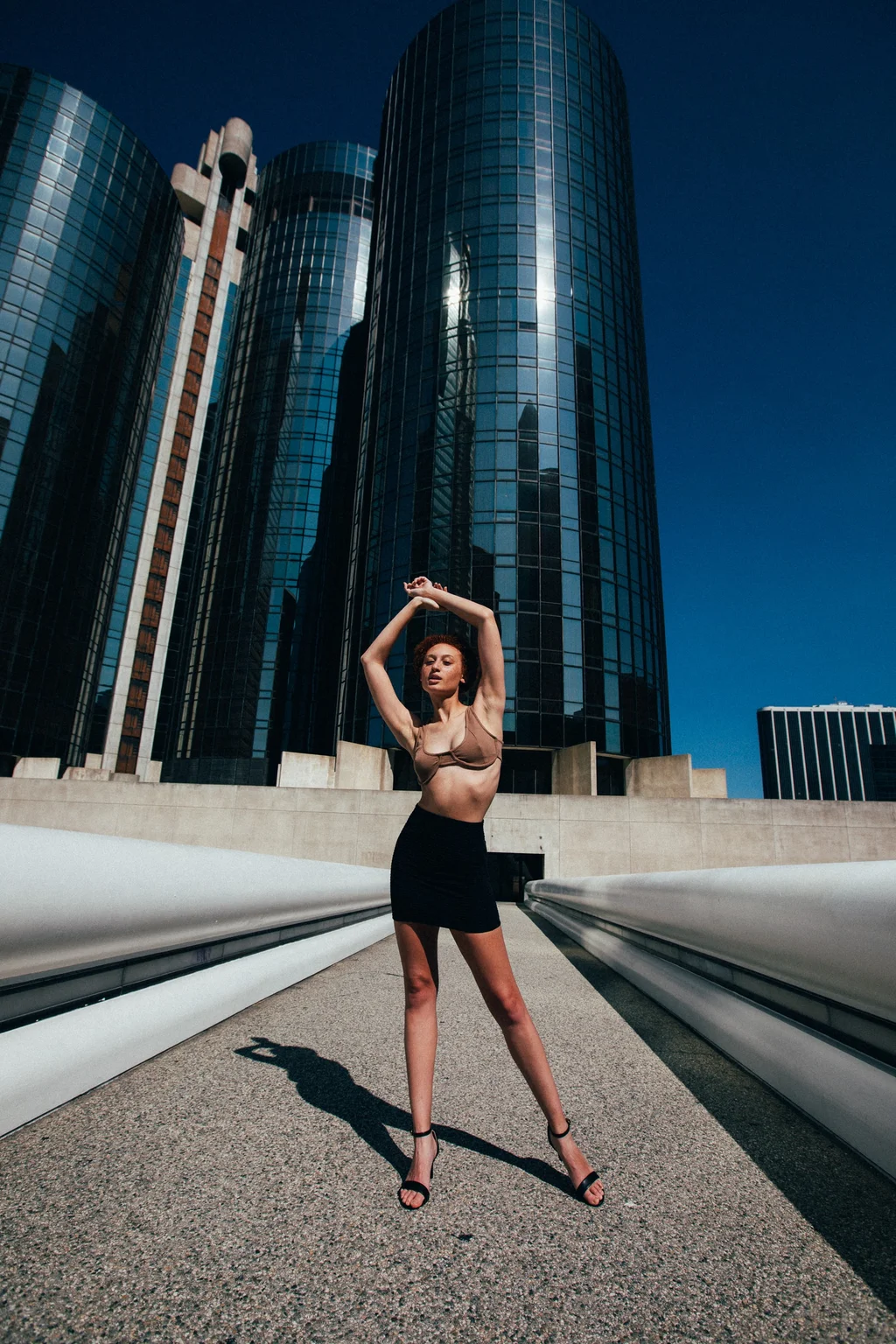 A full-length fashion portrait beneath glass skyscrapers