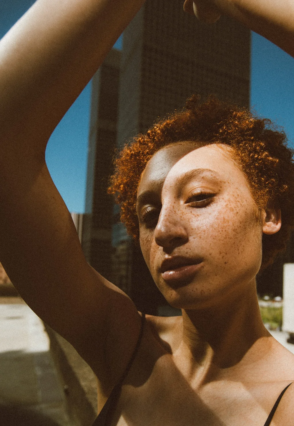 Sunlit close-up with raised arms and architectural lines