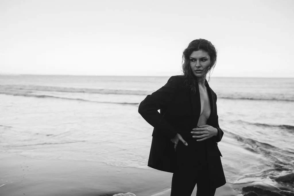 Black-and-white fashion portrait in a tailored suit beside the sea
