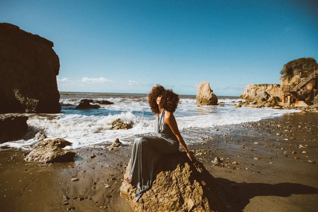 A flowing dress among sunlit rocks and breaking waves
