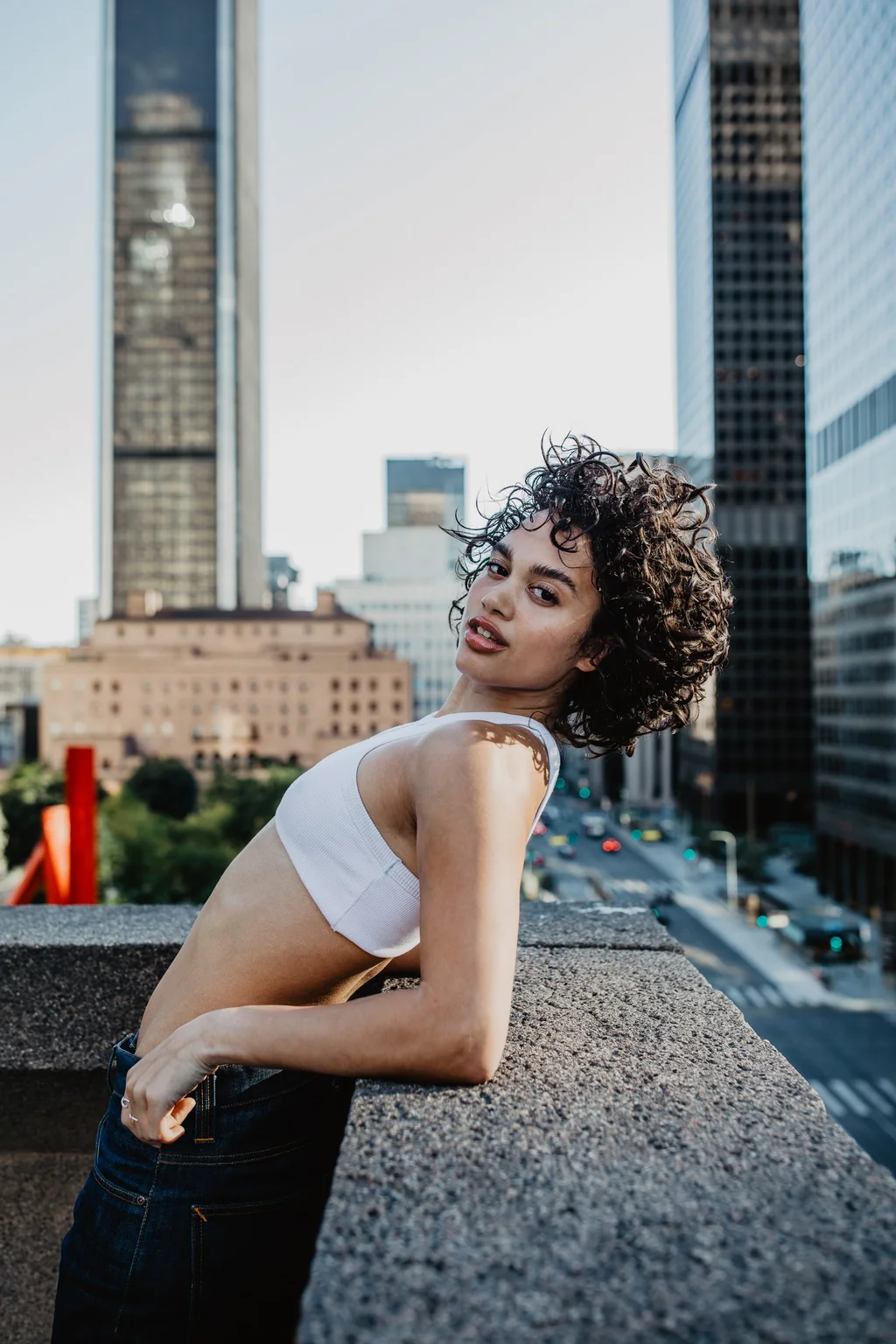 A rooftop portrait in white against tall city buildings