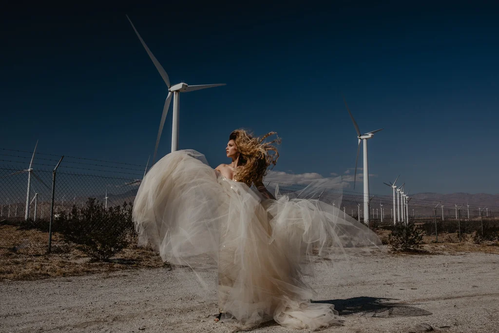 A flowing white dress in the wind beneath desert turbines