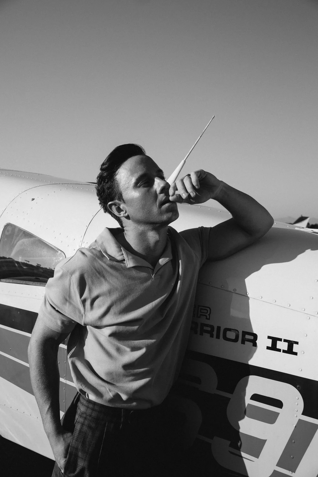 Black-and-white portrait leaning against a light aircraft