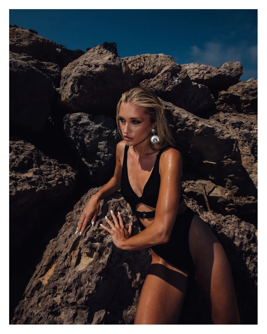 Swimwear portrait among sunlit coastal rocks